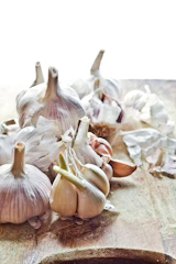 Close-up of fresh garlic heads with dew drops in natural light.
