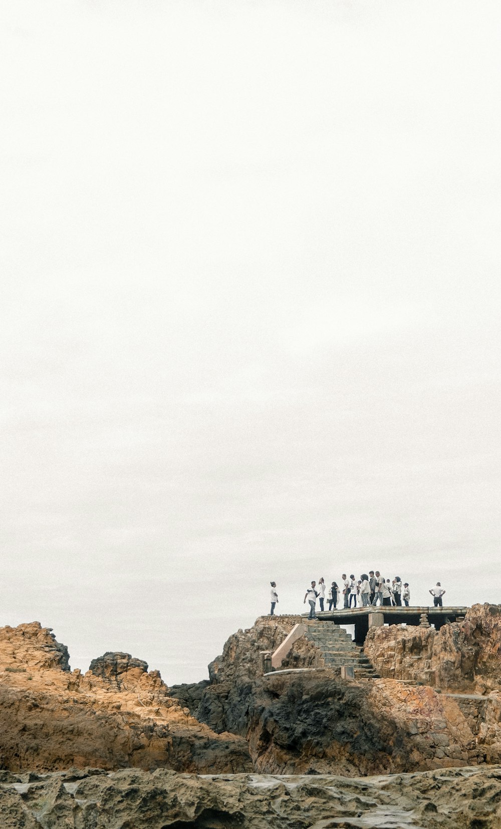 people standing on brown rock formation under white sky during daytime