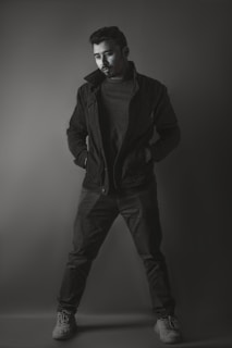 A sleek, minimal photo of a man wearing a modern black jacket in a soft-lit urban setting