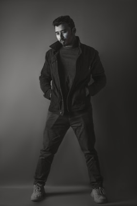 A sleek, minimal photo of a man wearing a modern black jacket in a soft-lit urban setting