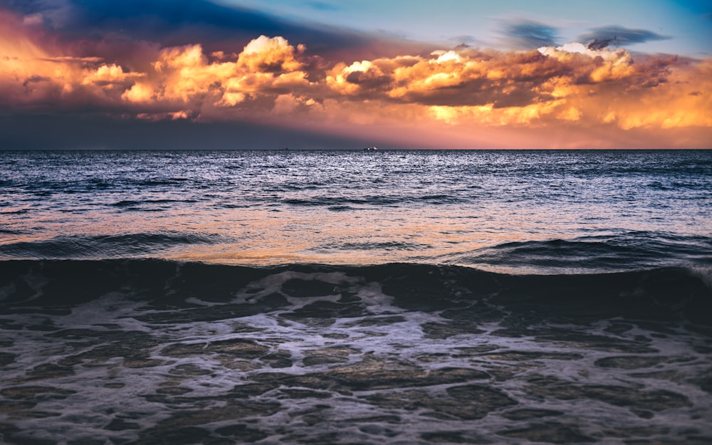 ocean waves crashing on shore during sunset