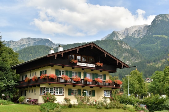 A picturesque mountain hut surrounded by vibrant greenery and colorful flowers.