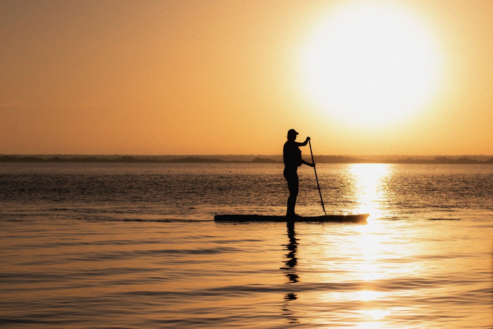 silhouette d’homme chevauchant sur un bateau pendant le coucher du soleil