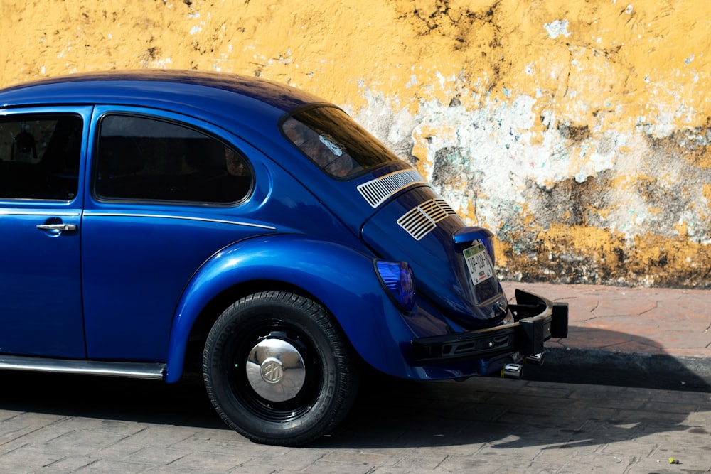 blue car parked beside yellow wall