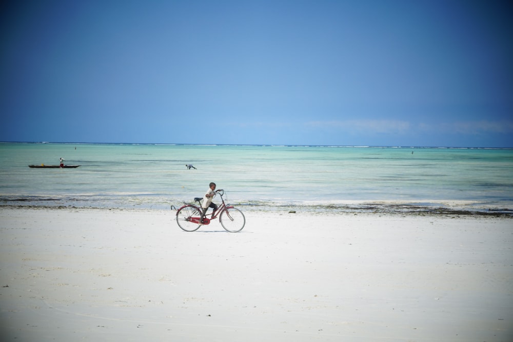 Mies ratsastaa polkupyörällä rannalla päiväsaikaan