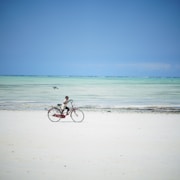 man riding bicycle on beach during daytime