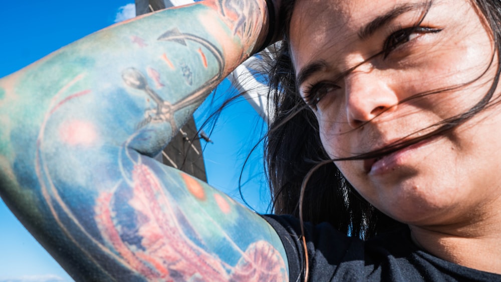 woman in black and white shirt with blue and red floral tattoo on left arm