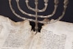 Hands holding a well-worn Torah scroll in a peaceful study setting.