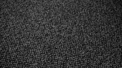 Close-up of a matte black fabric textured with subtle circuitry patterns glowing faintly.