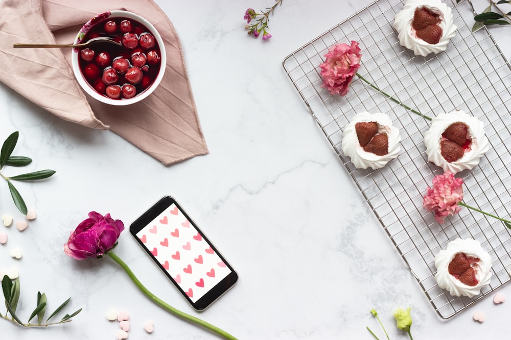 black and red iphone 5 c beside white ceramic mug with red and white liquid