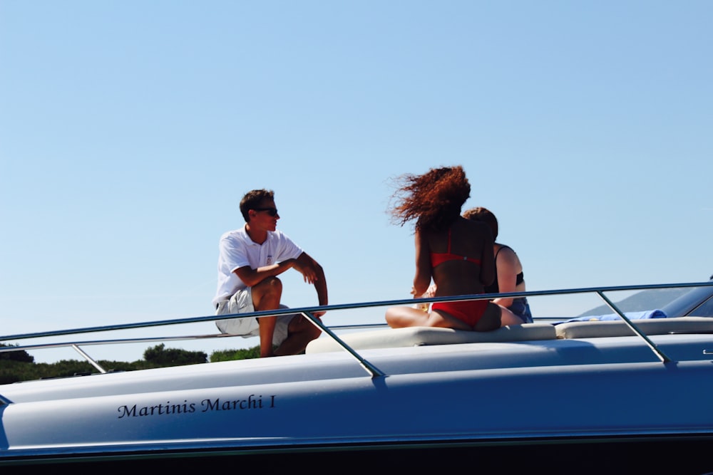 man and woman sitting on blue and white boat during daytime