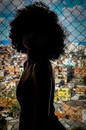 woman in black tank top standing beside chain link fence during daytime