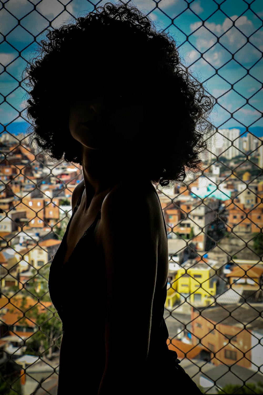 woman in black tank top standing beside chain link fence during daytime