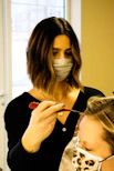 Payal Patel demonstrating hair patch application technique in a bright training room.