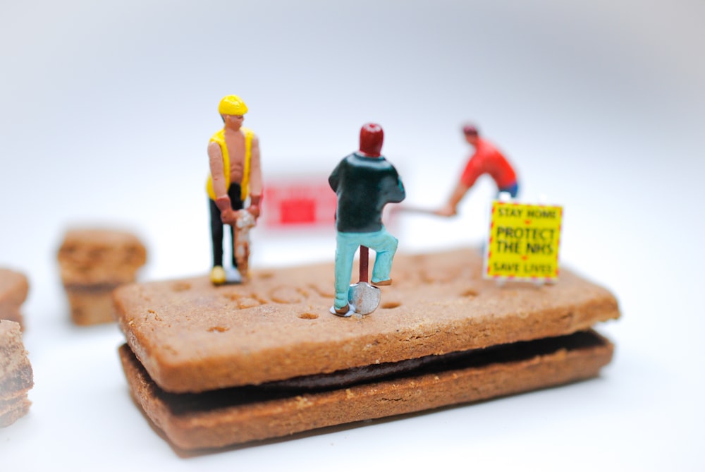 Homme en costume rouge et bleu debout sur une figurine de table en bois marron