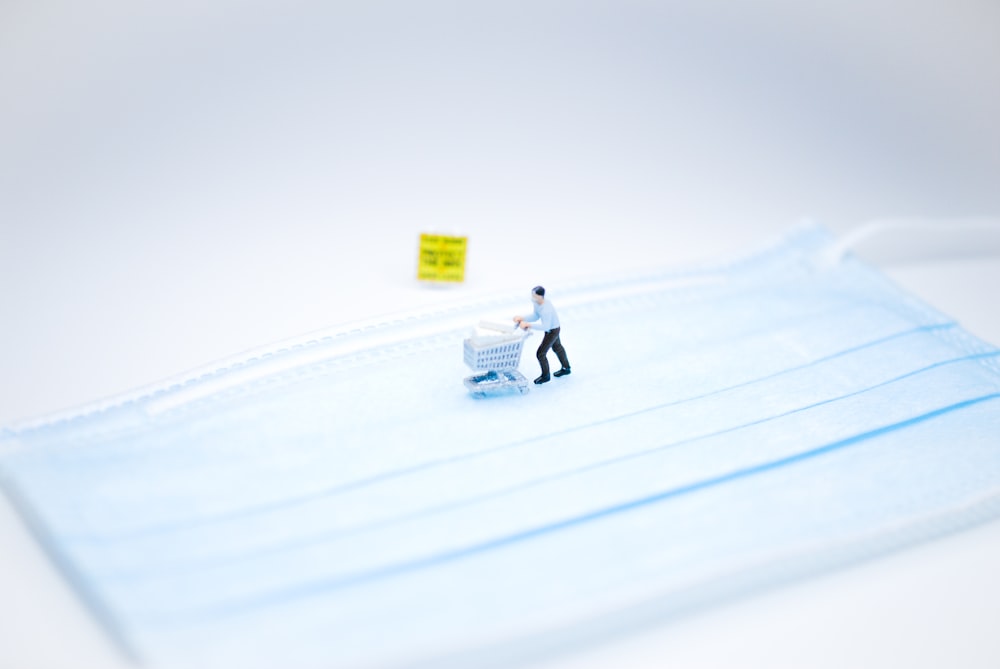 person in white jacket riding white snow sled on snow covered field during daytime