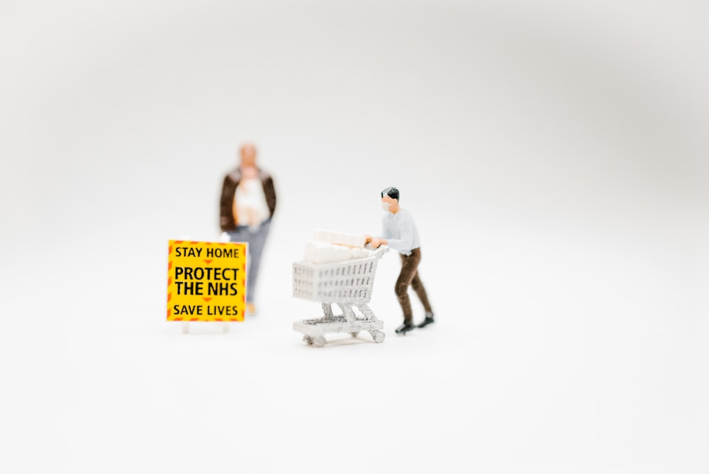 man in white t-shirt and black pants holding white plastic shopping basket