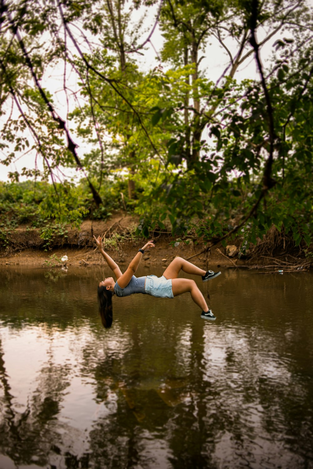 woman in blue denim shorts sitting on river bank during daytime