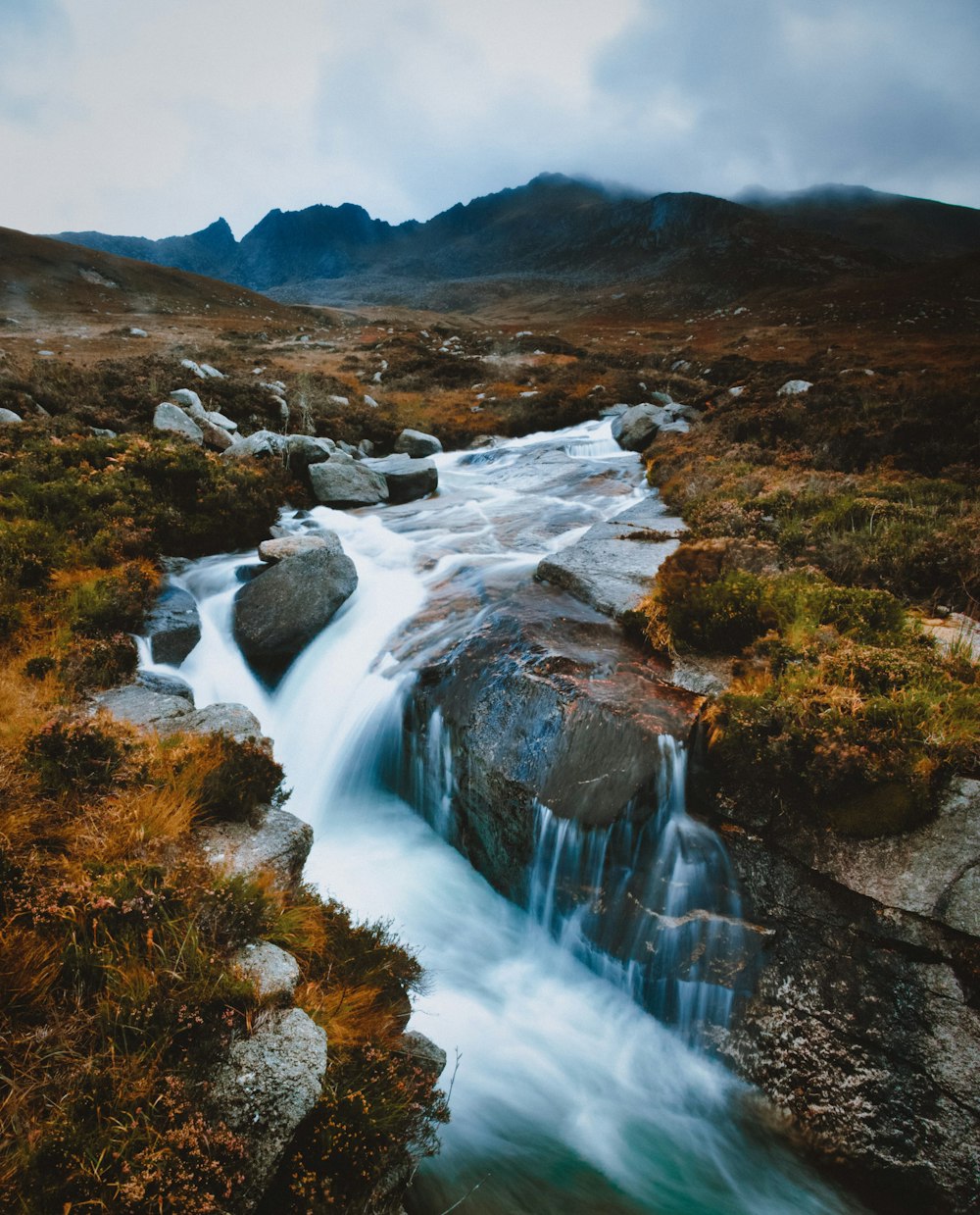 water falls on brown rocky mountain during daytime