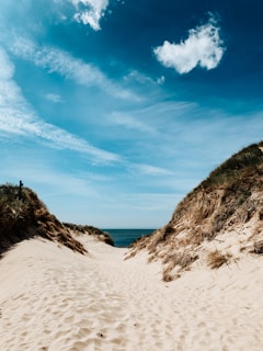 white sand near brown mountain under blue sky during daytime