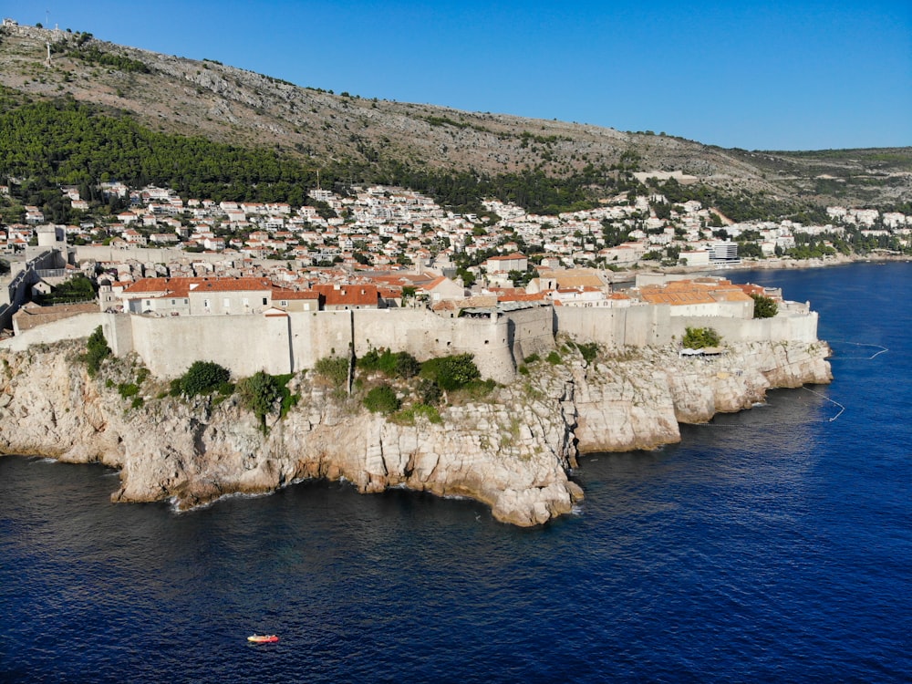 white and brown concrete building on cliff near body of water during daytime