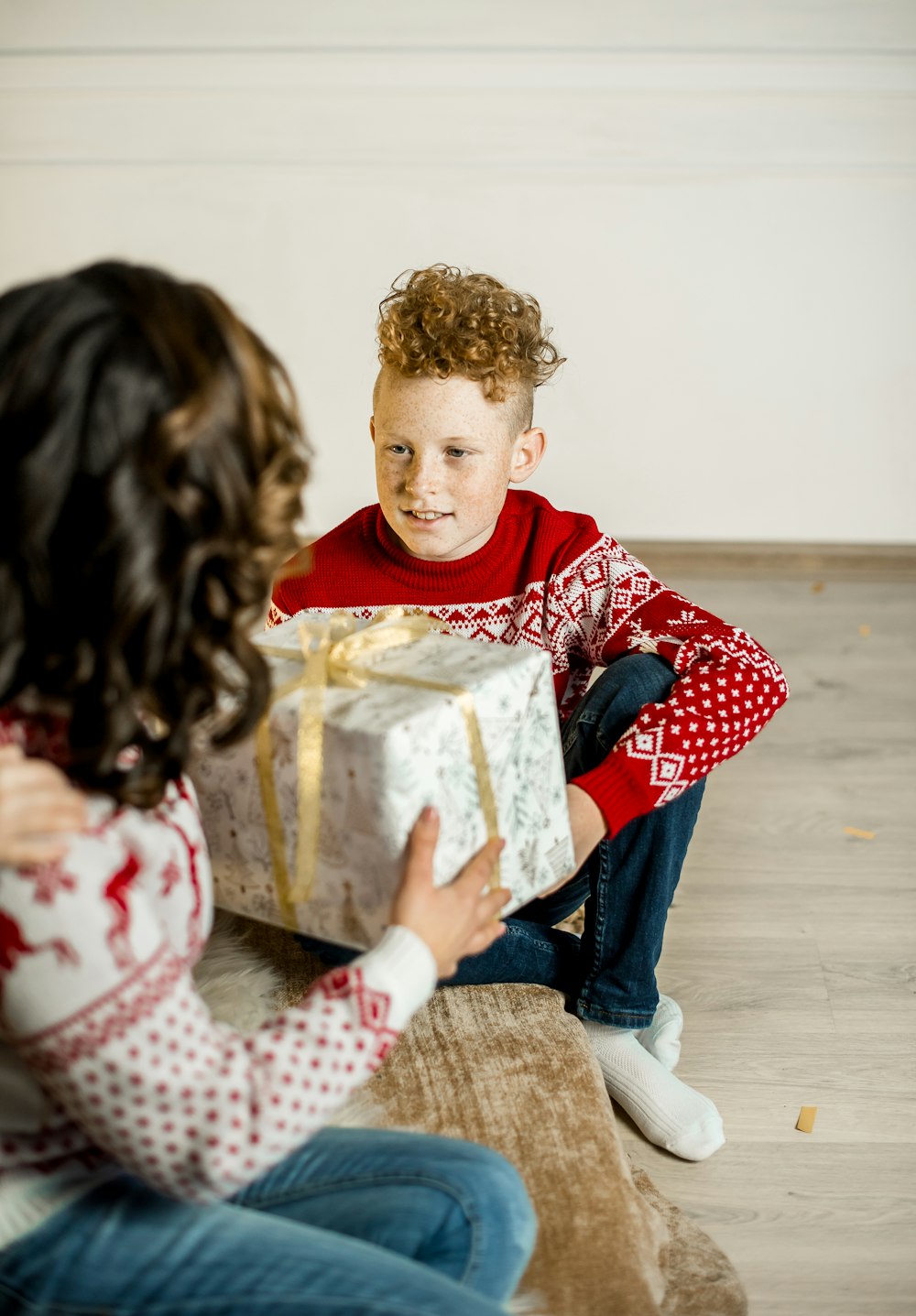 a little boy sitting on the floor holding a present