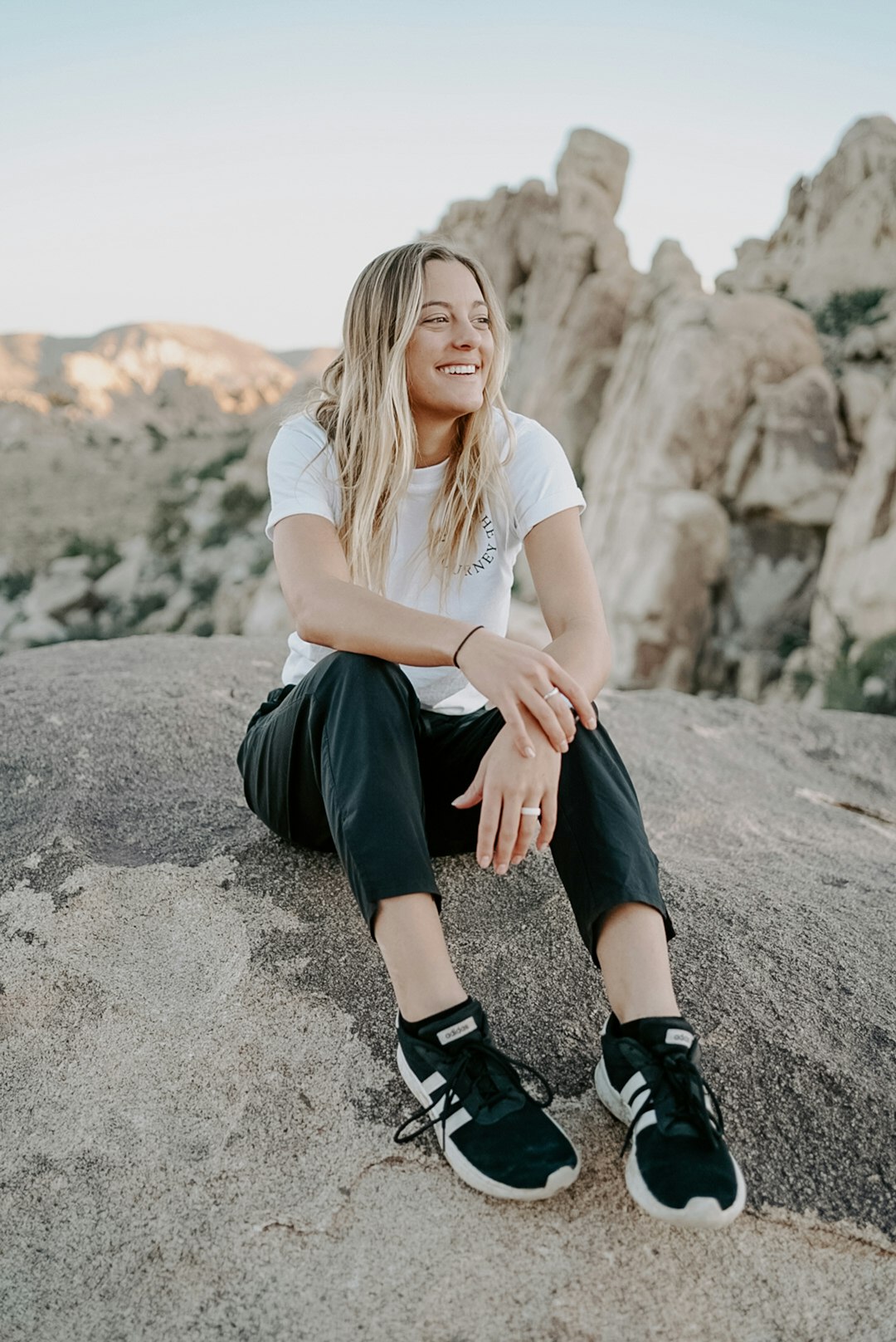 woman in white shirt and black skirt sitting on gray rock during daytime