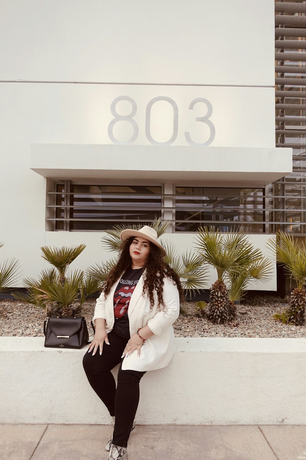 woman in white long sleeve shirt and black pants sitting on white concrete bench