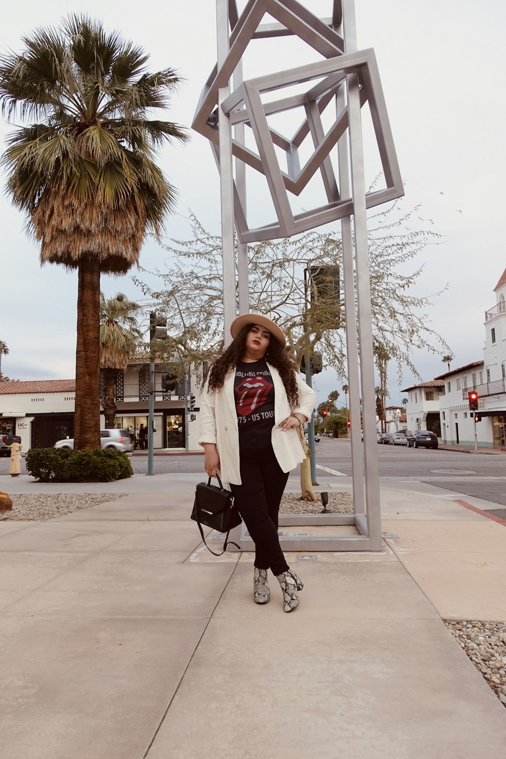 woman in white shirt and black skirt standing on sidewalk during daytime