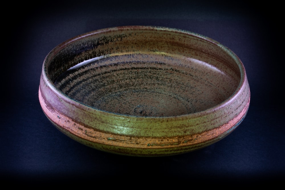 braune runde Keramikschale auf schwarzer Oberfläche