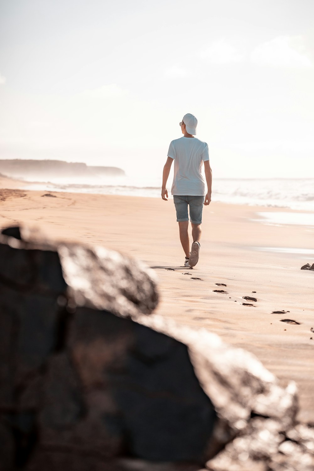 Mann in weißem Hemd und braunen Shorts tagsüber am braunen Sandstrand