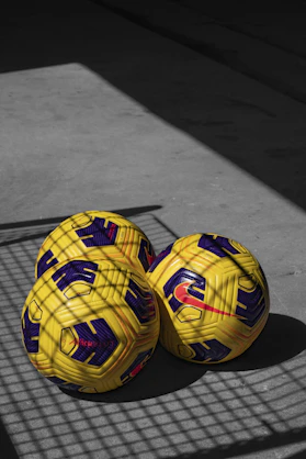 yellow and black soccer ball on gray wooden floor