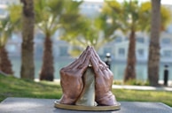 An artistic rendering of intertwined hands in prayer, rendered with delicate brush strokes and warm tones.