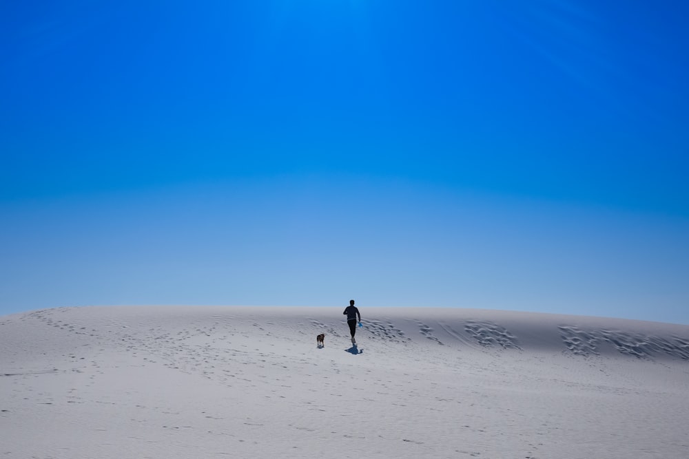 person walking on white sand during daytime