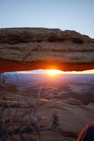A panoramic view of Windstone Arch at sunset with vibrant orange and pink skies