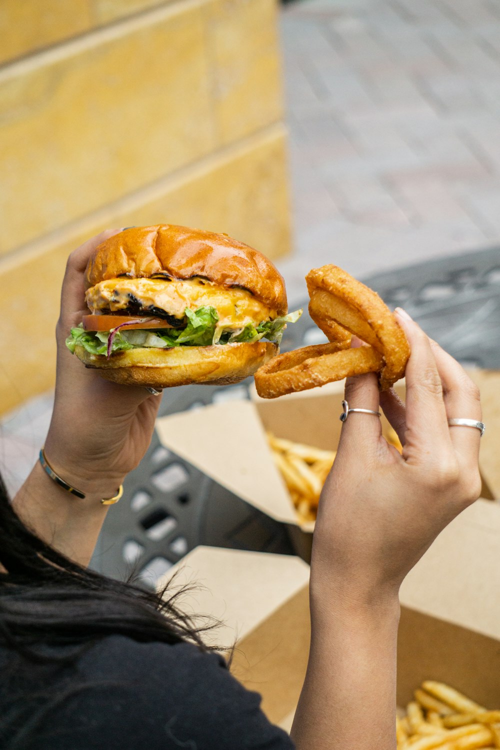 person holding burger with lettuce and tomato