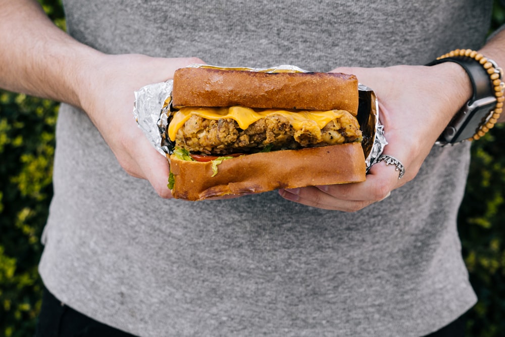 person holding burger with cheese