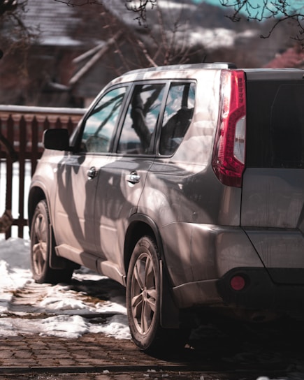 Mobile technician carefully installing a windshield on a silver SUV in a sunny driveway.