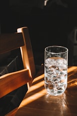 clear drinking glass on brown wooden chair