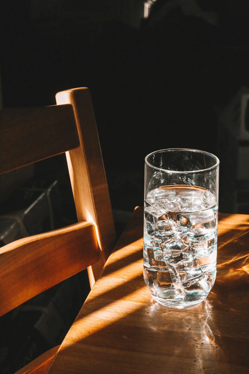 clear drinking glass on brown wooden chair