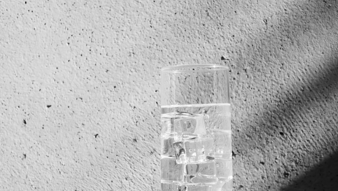 grayscale photo of water droplets on clear drinking glass