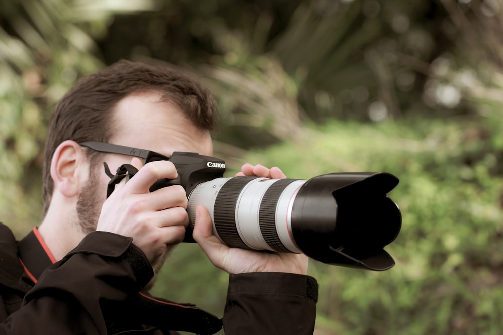 man in brown jacket holding black dslr camera