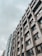 A modern office building with a geometric facade featuring numerous windows. The structure appears tall and is set against a cloudy sky, giving an urban and professional feel.