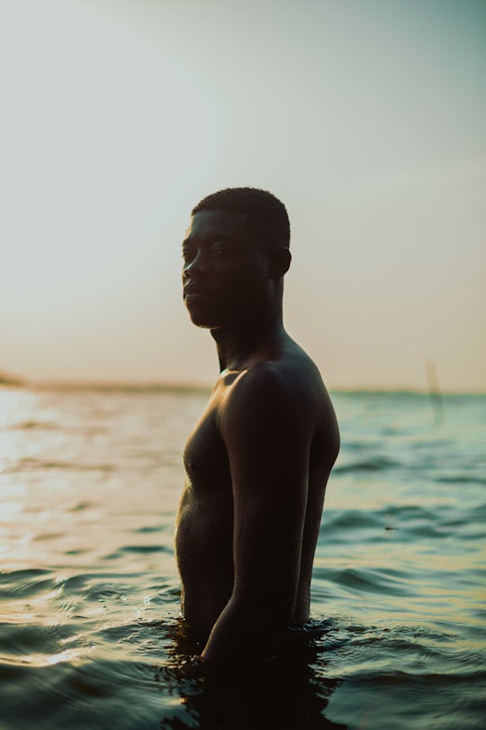 topless man standing on water during daytime in Accra Ghana