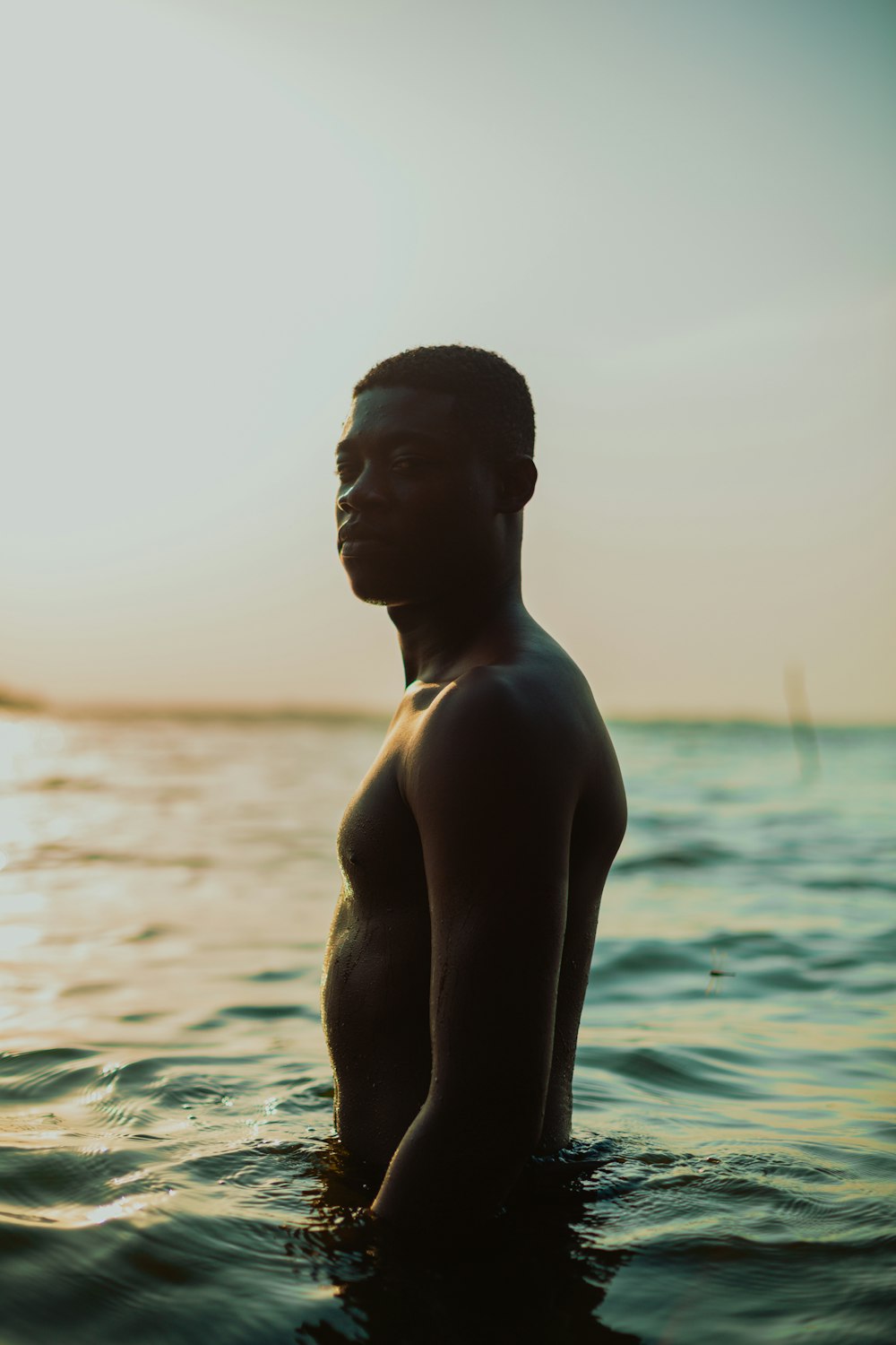 topless man standing on water during daytime