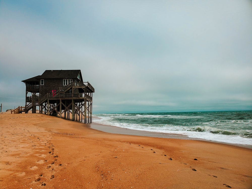 casa di legno marrone sulla spiaggia durante il giorno