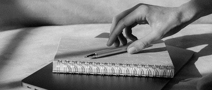 grayscale photo of persons hand on book