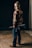 man in brown and black camouflage jacket and blue denim jeans holding black rifle