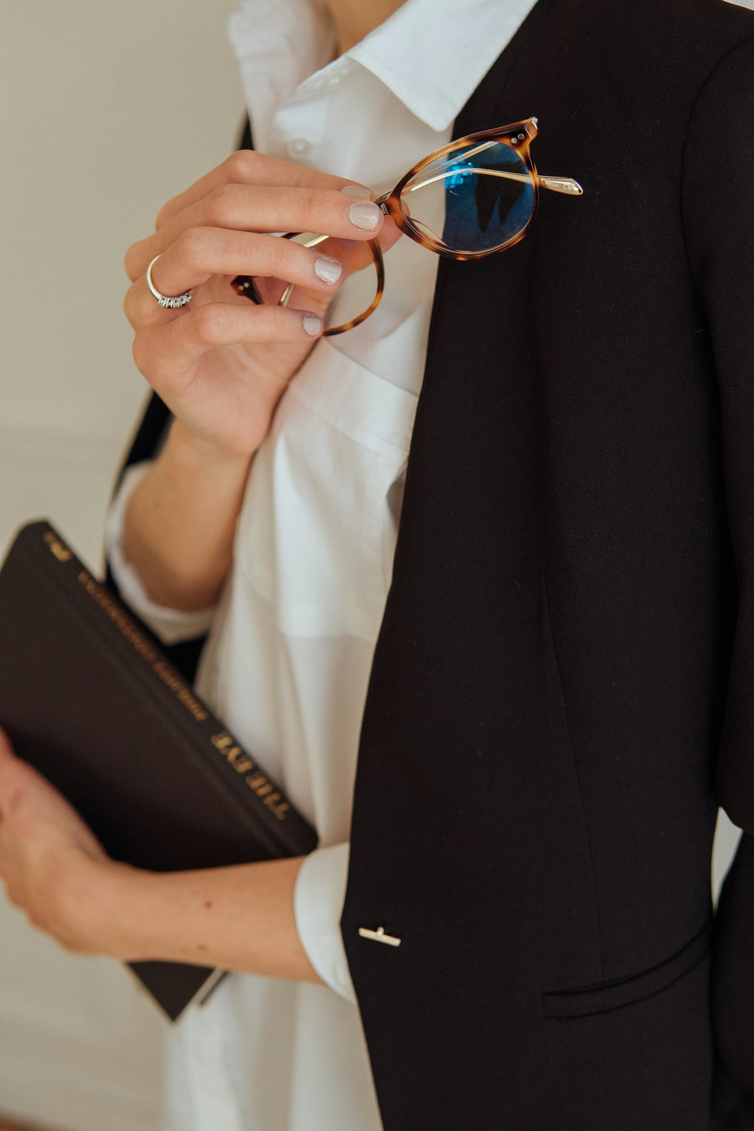 person in black blazer holding black leather bag