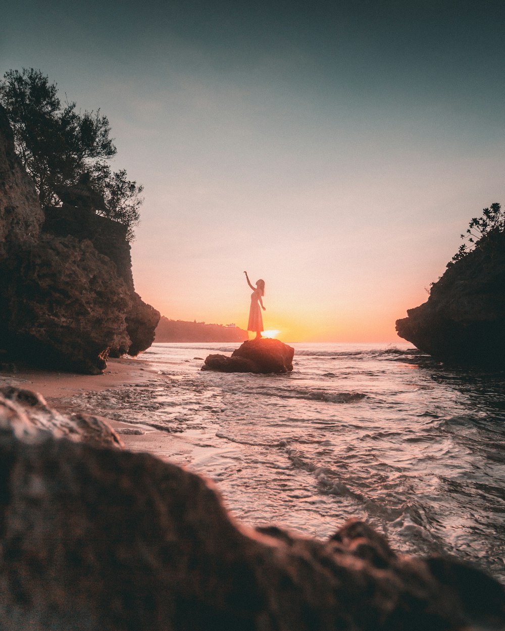 person standing on rock formation near body of water during daytime